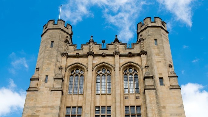 The two towers of the 1920s section of the HH Wills Physics Building. The building is against a cloudy blue sky.